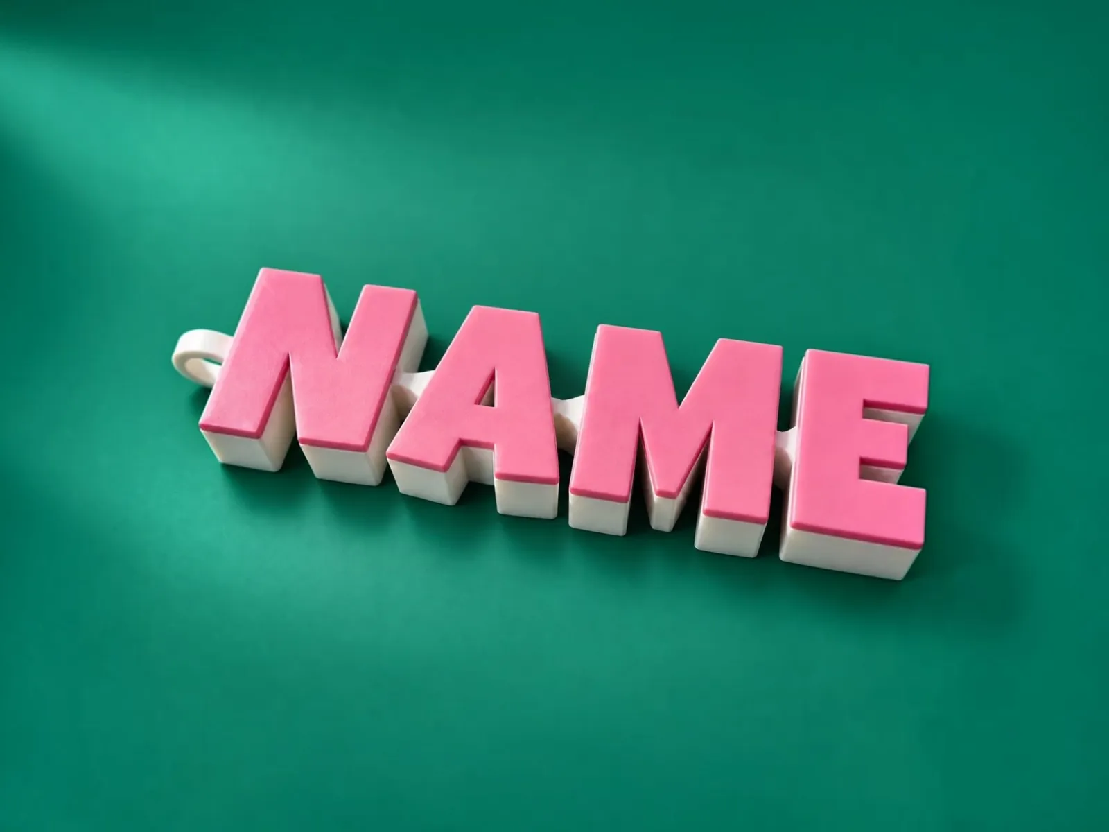 A 3D-printed articulated NAME keychain with pink letters on an ivory body, on a green background.